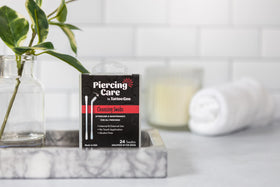 Tattoo Goo swab used on an ear piercing illustrating hygienic hands-free cleaning