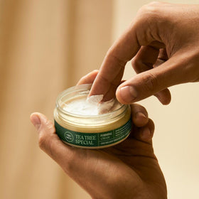 Hand holding Tea Tree forming cream 3 oz jar for size comparison and portability benefit