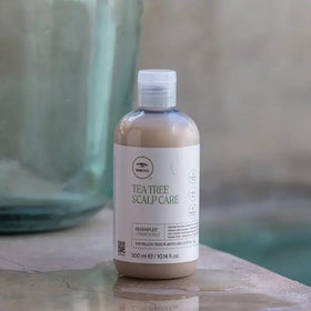 Tea Tree bottle in hand to show 33.8 fl. oz. scale and value