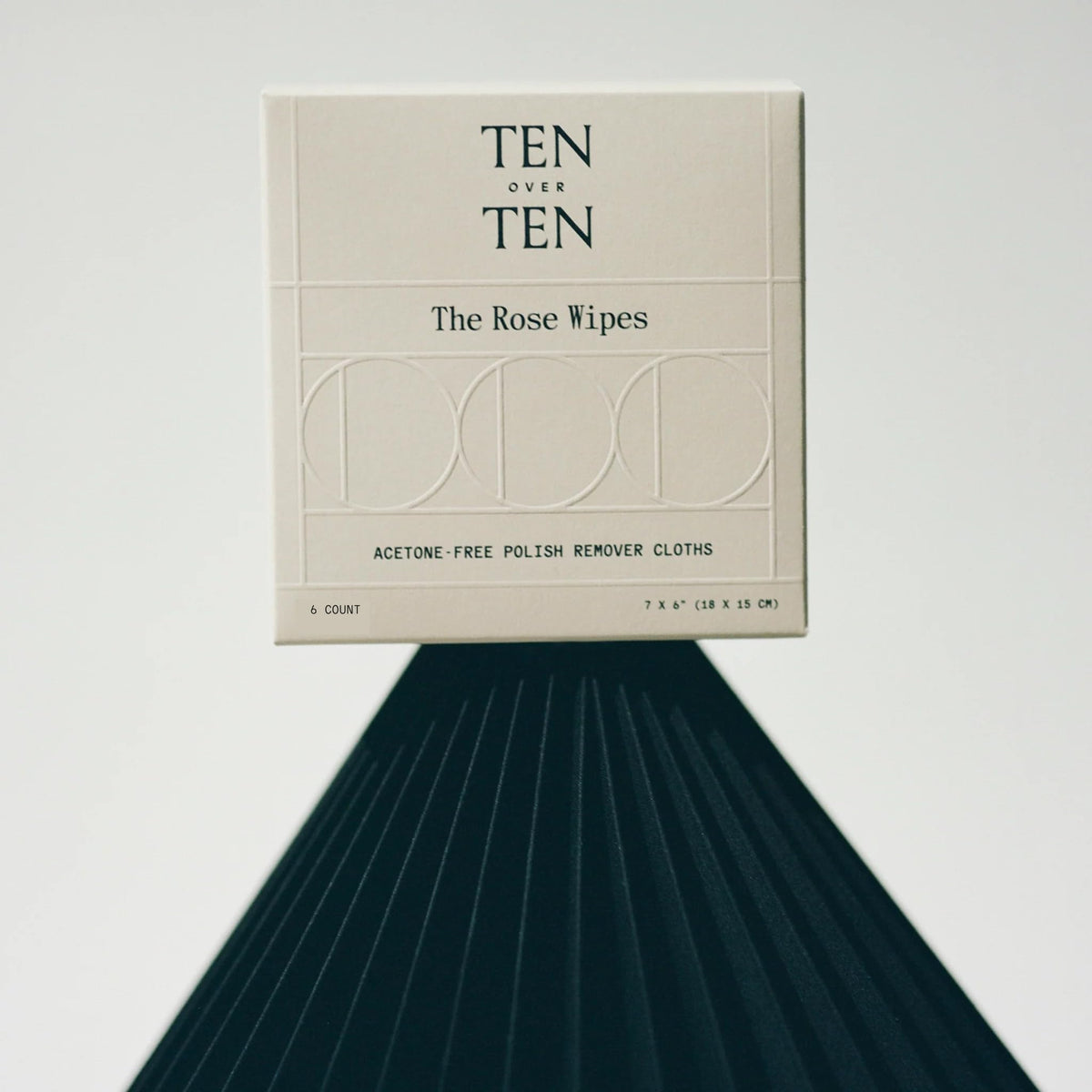 Tenoverten wipe held in hand beside purse illustrating travel-ready convenience and low-odor benefit
