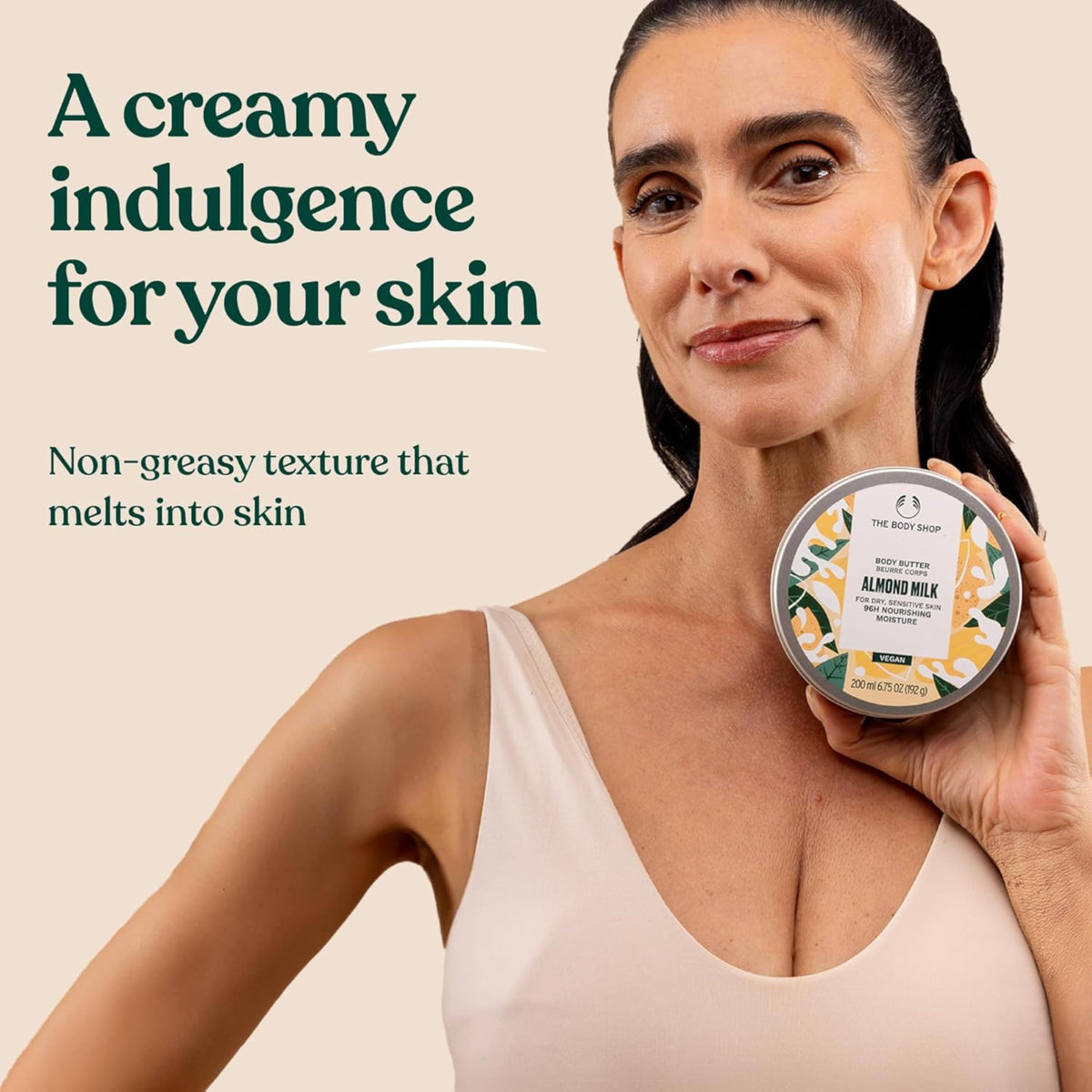 200 ml The Body Shop Almond Milk Body Butter beside a ruler and hand to show scale and travel-friendly size