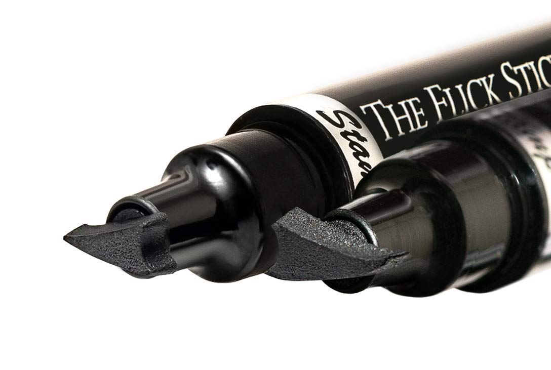 the flick stick next to a pen for scale illustrating compact travel size
