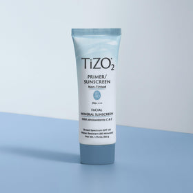 TIZO tube next to hand for scale highlighting convenient 1.75 oz travel-friendly size