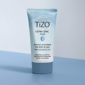 TIZO next to everyday objects showing 3.5 oz travel-friendly size