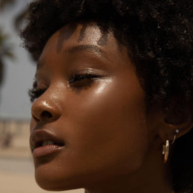 Tower 28 SuperDew on cheekbone close-up showing natural glass-skin glow benefit