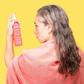 Umberto Giannini bottle in a beach bag for on-the-go hair refreshment