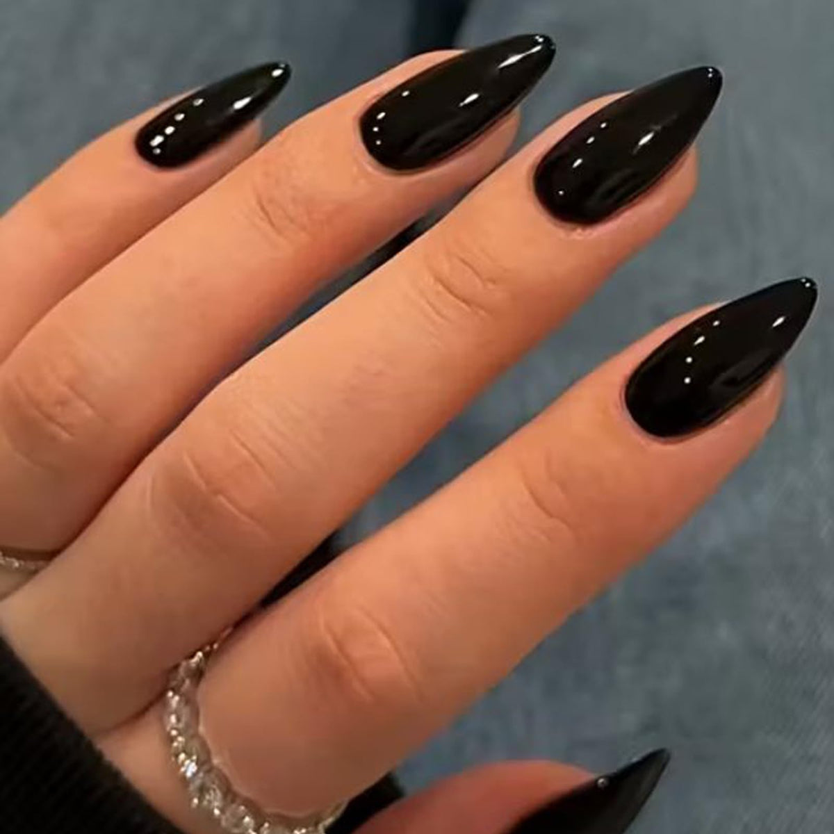 UNA GELLA front view showing medium almond glossy black nails, polished finish benefit