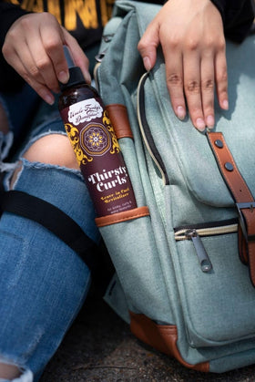 Uncle Funky's Daughter bottle in hand illustrating size and portability for on-the-go curl refreshment