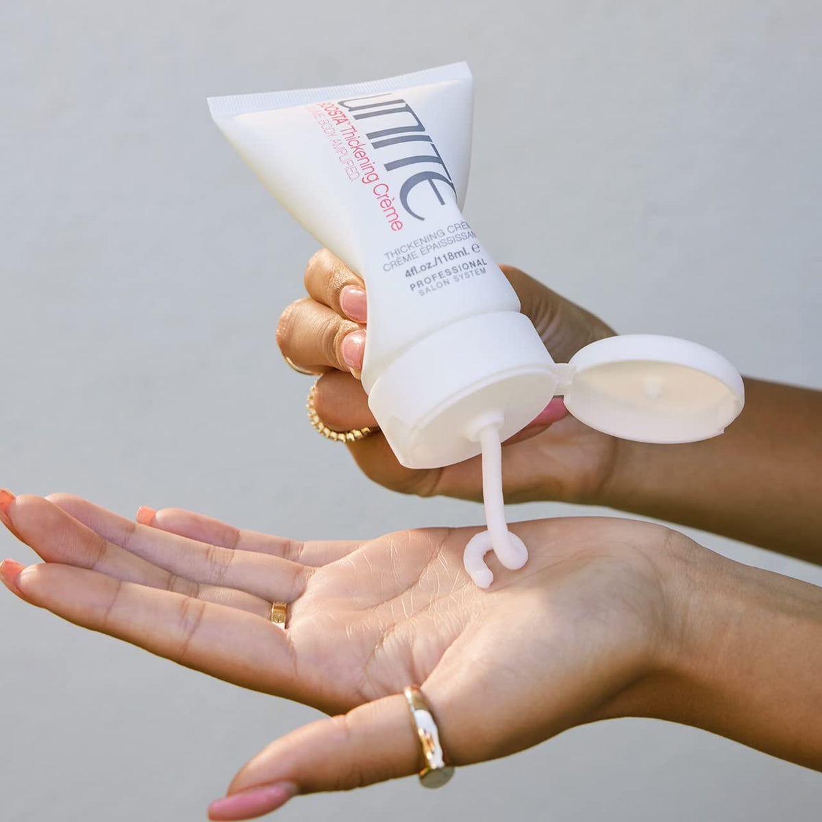 UNITE BOOSTA label and 4 fl oz size next to hand for scale and ingredient clarity