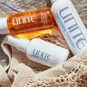 UNITE LIQUID Volume 4 fl oz next to a hand for scale showing portable styling benefit