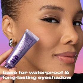 Urban Decay bottle beside eyeshadow palette to boost pigment payoff