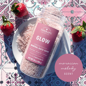 Village Naturals Therapy jar beside bathtub and candles demonstrating relaxing ambiance benefit