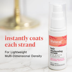 viviscal bottle beside a hand showing 1.69 fl oz size for travel-friendly use