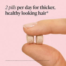 Woman holding Viviscal tablet demonstrating simple twice-daily routine benefit