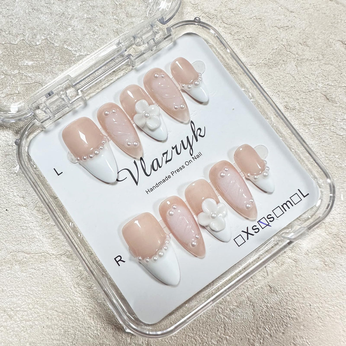 vlazryk finished manicure angled shot showing polish, pearl and floral accents