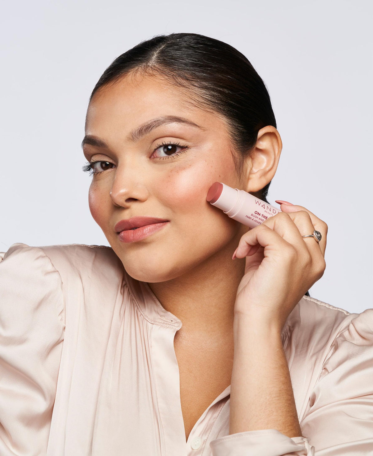 Wander Beauty applying blush to cheeks demonstrating quick touch-up benefit