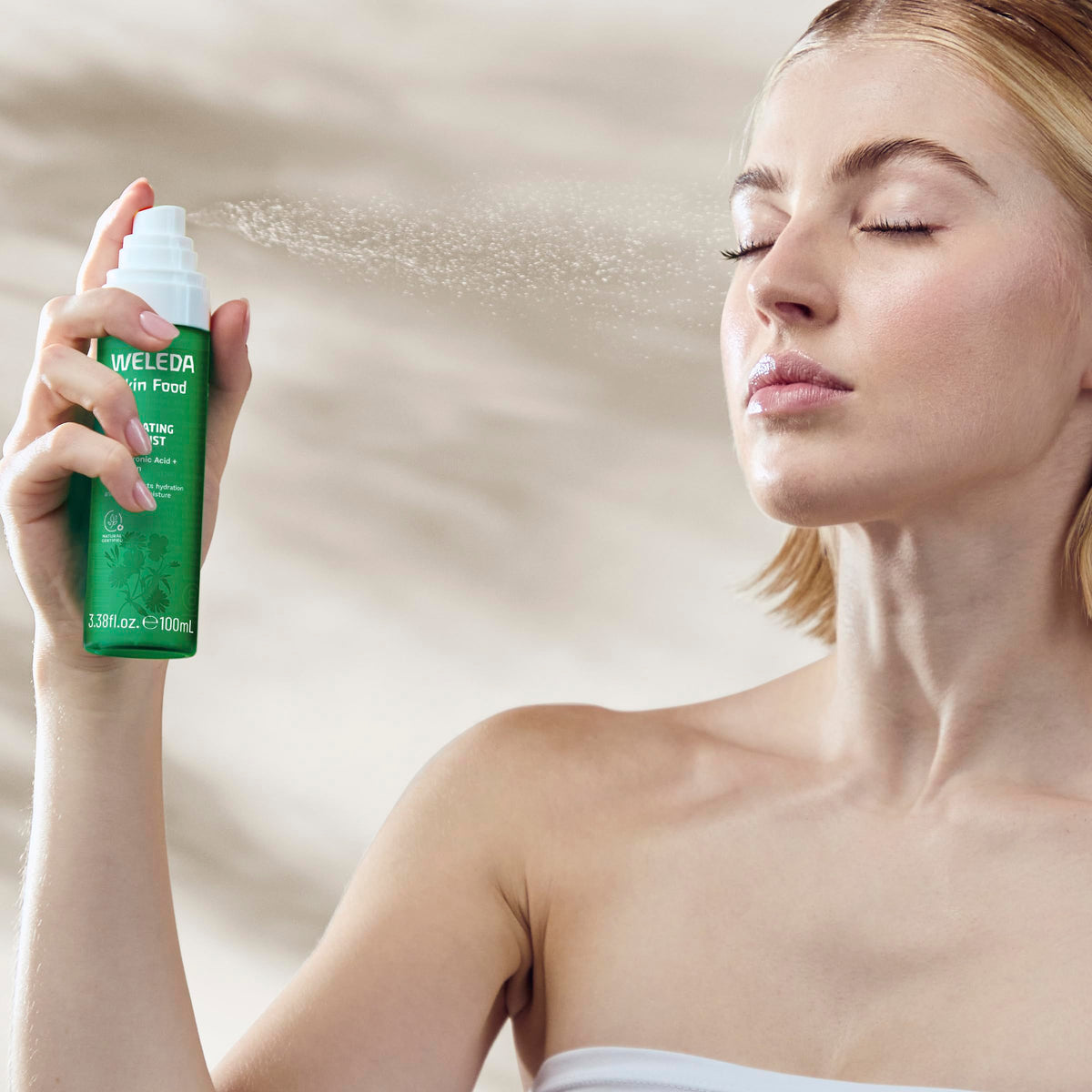 Weleda Skin Food mist held in hand to show size and travel-friendly benefit