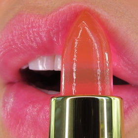 Winky Lux balm being swiped on lips, demonstrating sheer pink tint